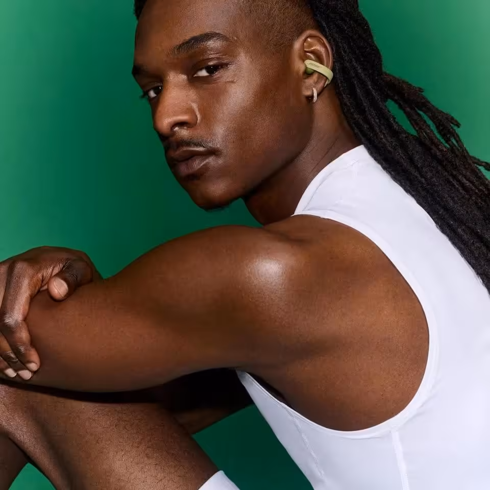 Homme portant des Bose Ultra Open Earbuds vertes, portrait studio sur fond vert