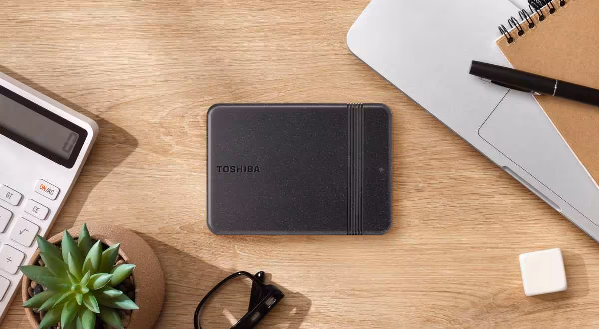 Canvio Ready : Toshiba relance son HDD portable avec coque recyclée et jusqu'à 4 To 2 Disque dur portable Toshiba Canvio Ready posé sur un bureau avec calculatrice, plante et carnet