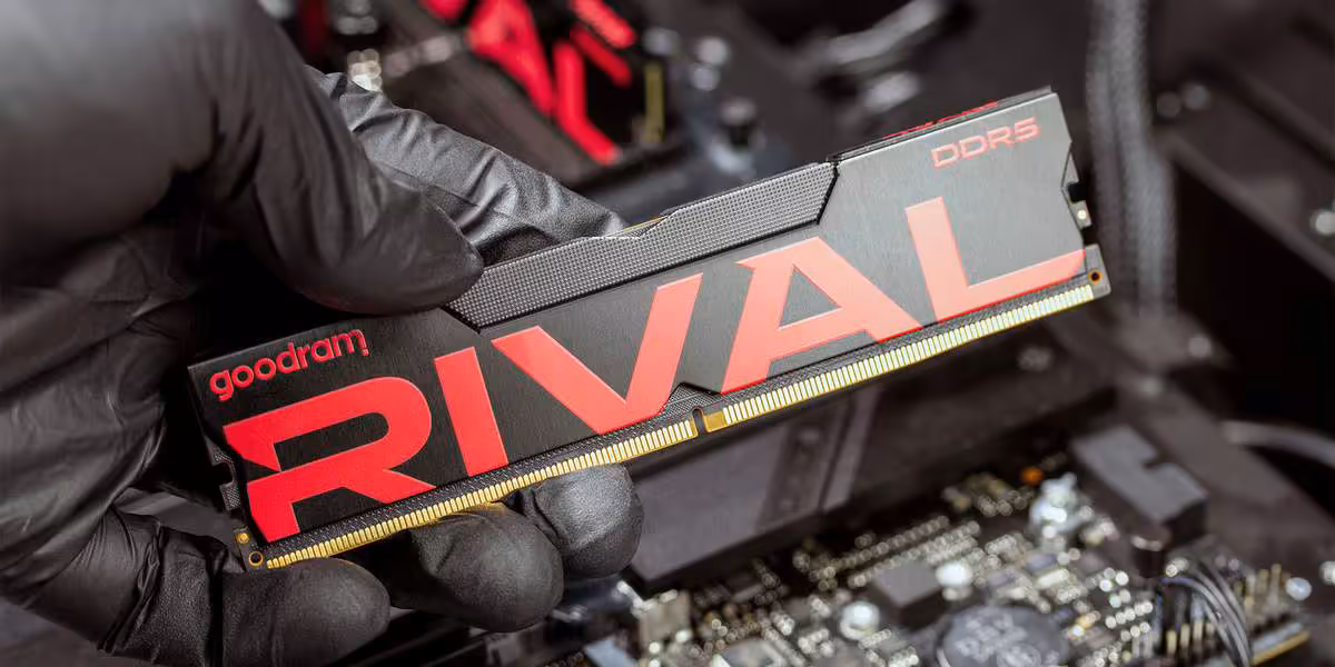 Goodram RIVAL Charge DDR5 : jusqu’à 6800 MT/s et 64 Go pour les PC gaming 5 Main gantée tenant une barrette mémoire Goodram RIVAL DDR5 au-dessus d’une carte mère