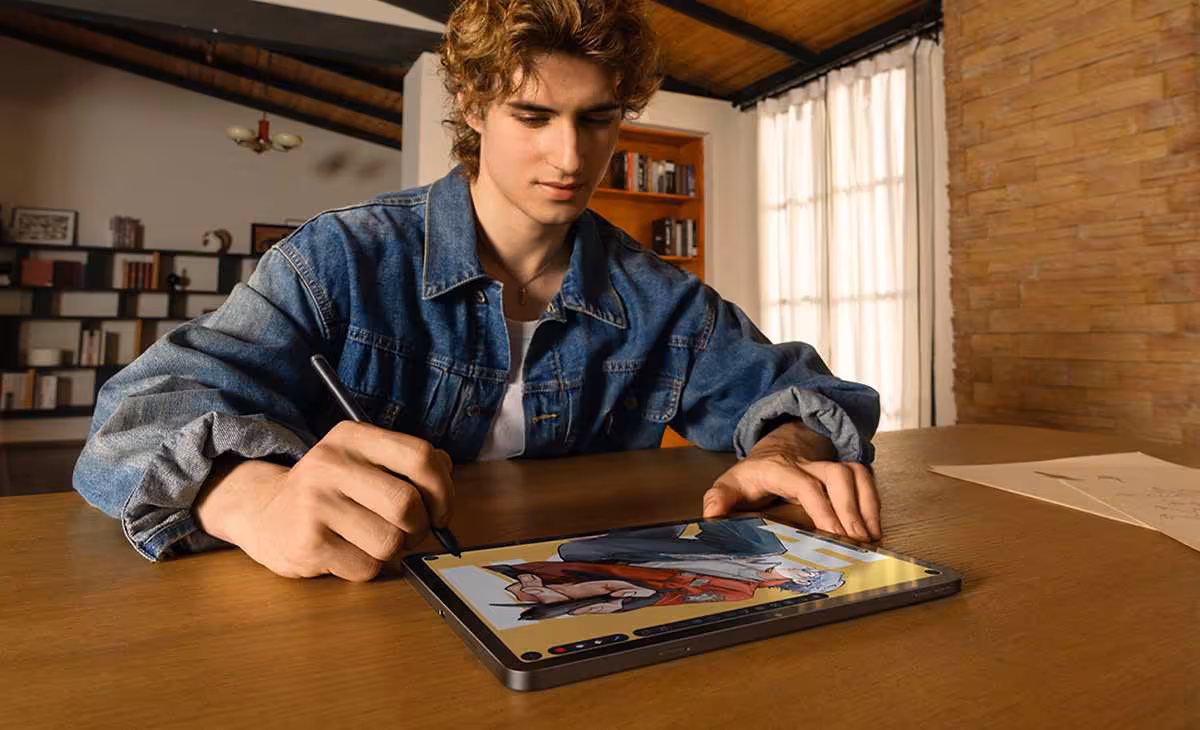 Jeune homme dessinant sur une tablette graphique Huion Kamvas Pad 12 avec stylet, dans un intérieur lumineux