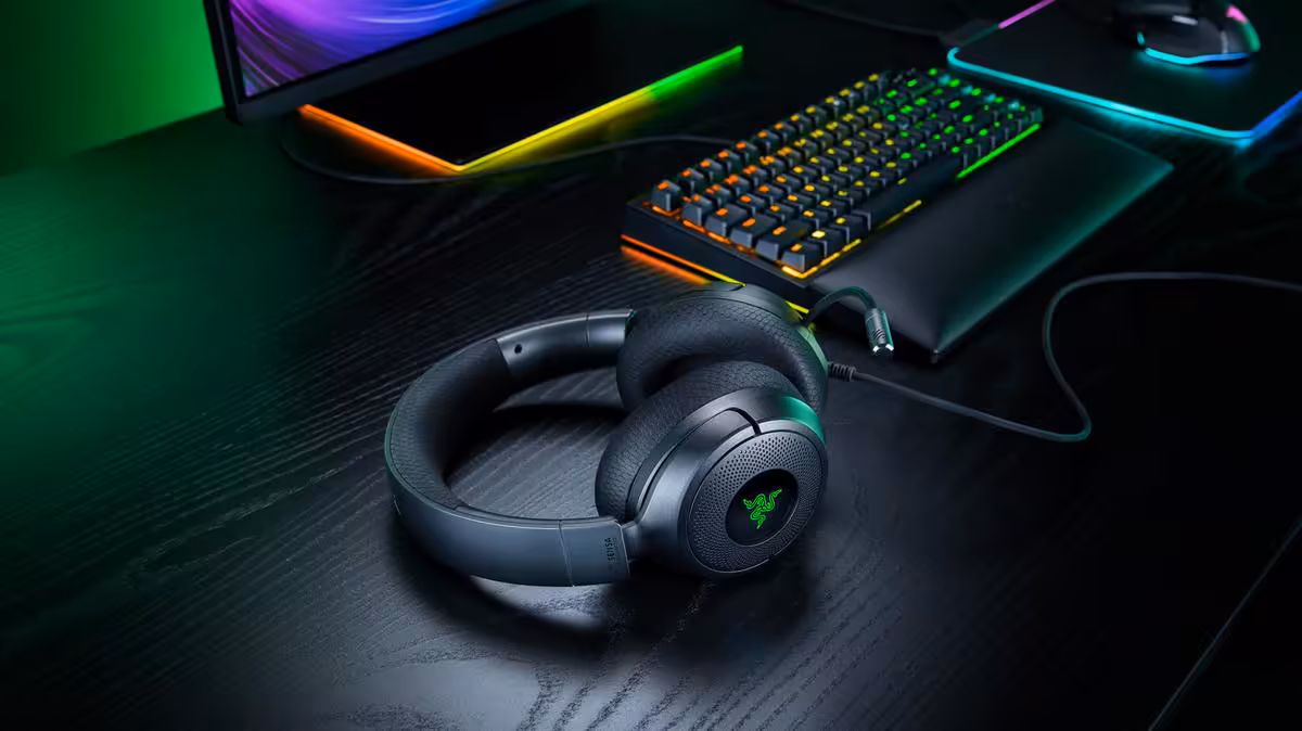 Casque Razer noir sur bureau gaming avec clavier RGB et écran, ambiance néon
