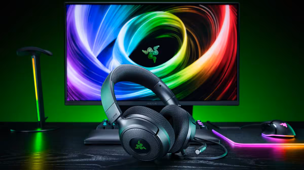 Casque gaming Razer noir posé devant un écran RGB vert et violet sur bureau gaming
