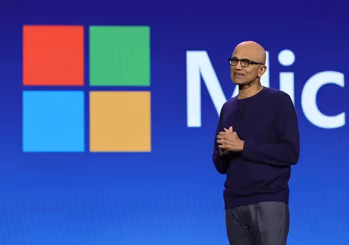Satya Nadella sur scène devant le logo Microsoft lors d’une conférence