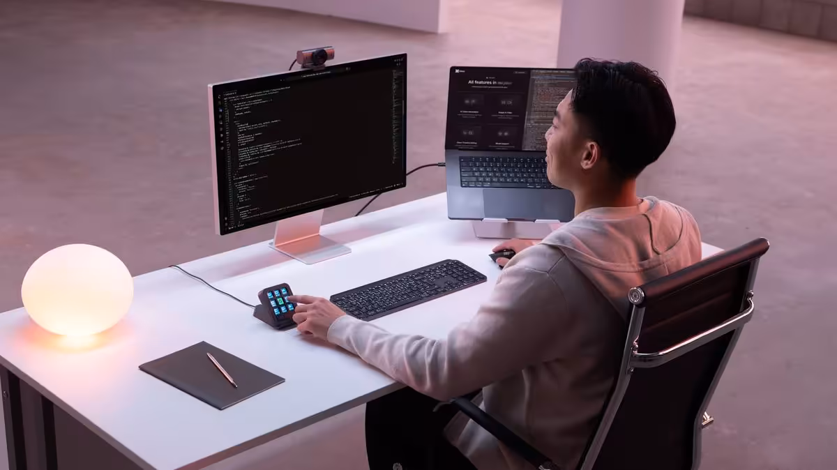 Bureau de travail avec utilisateur, clavier, écran et Logitech MX Keypad utilisé à côté de l’ordinateur
