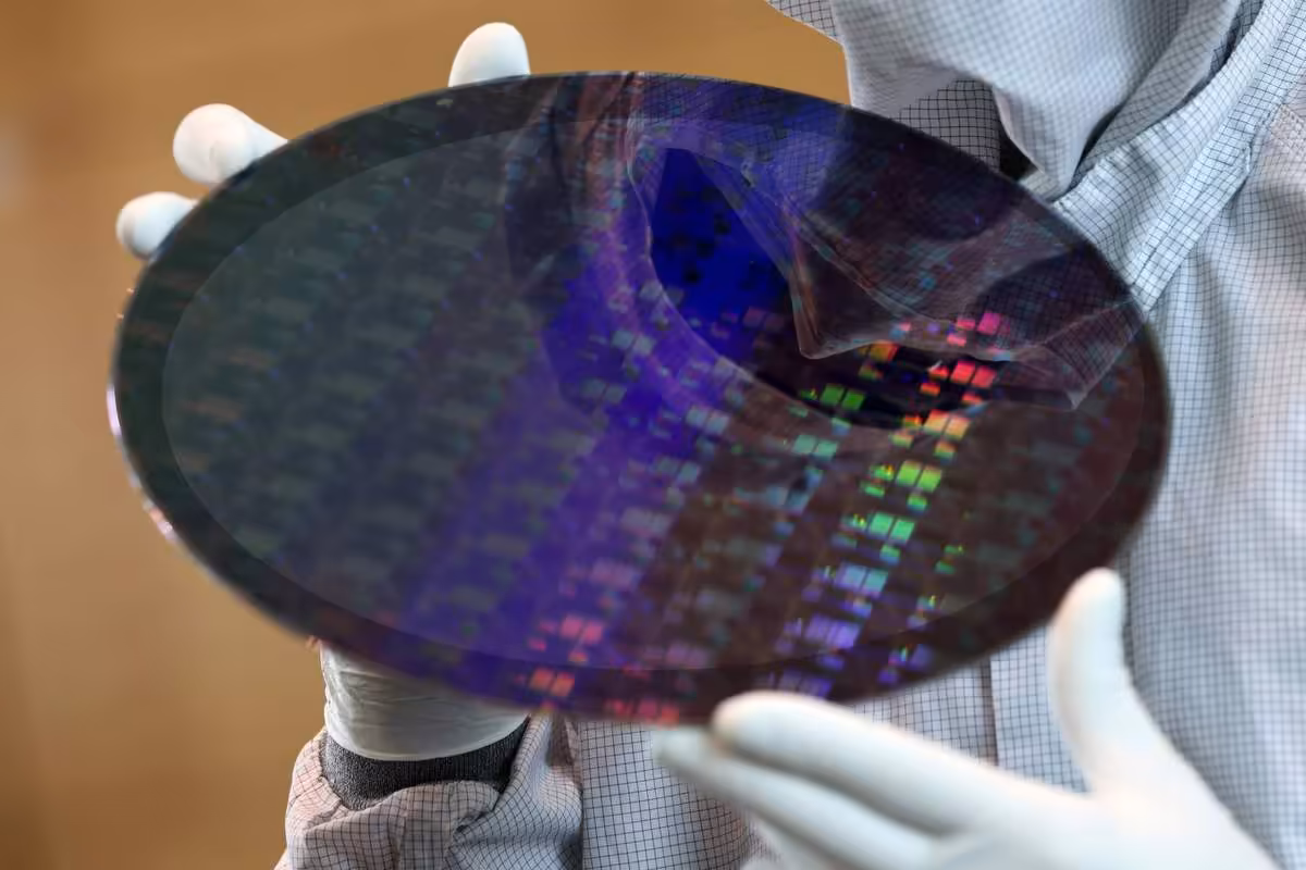 Technicien en salle blanche tenant un wafer de silicium aux motifs de circuits colorés