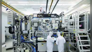 Techniciens en combinaison blanche devant une machine ASML EUV High NA dans une salle blanche industrielle