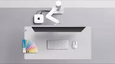 Poste de travail Apple minimaliste avec moniteur, clavier, souris et nuancier de couleurs BenQ sur tapis gris.