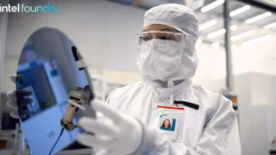 Technicien Intel Foundry en combinaison stérile manipulant un équipement dans une salle blanche de fabrication de puces