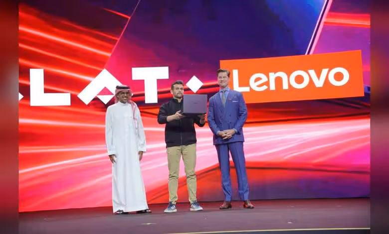 Lenovo Arabie saoudite : premier PC portable assemblé à Riyad, cap sur 2026 1 Trois hommes sur scène devant le logo Lenovo, l’un présentant un PC portable Lenovo brun foncé ouvert