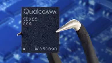Puce modem 5G Qualcomm Snapdragon X65 SDX65 tenue par une pince sur fond de circuit imprimé bleu