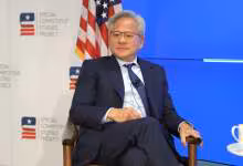 Jensen Huang, PDG de NVIDIA, assis lors d’une conférence du Special Competitive Studies Project devant écran bleu