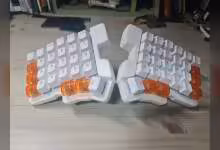 Clavier split magnétique blanc à touches transparentes orange, vue de face sur bureau en bois
