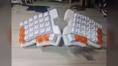 Clavier split magnétique blanc à touches transparentes orange, vue de face sur bureau en bois