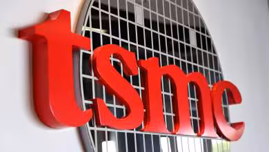 Logo rouge TSMC en relief devant une représentation circulaire de wafer de semi-conducteurs