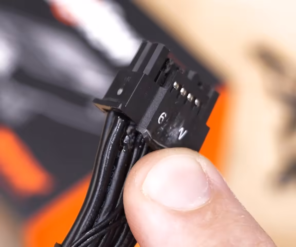 Connecteur d’alimentation 12V-2x6 noir de carte graphique, gros plan tenu entre les doigts
