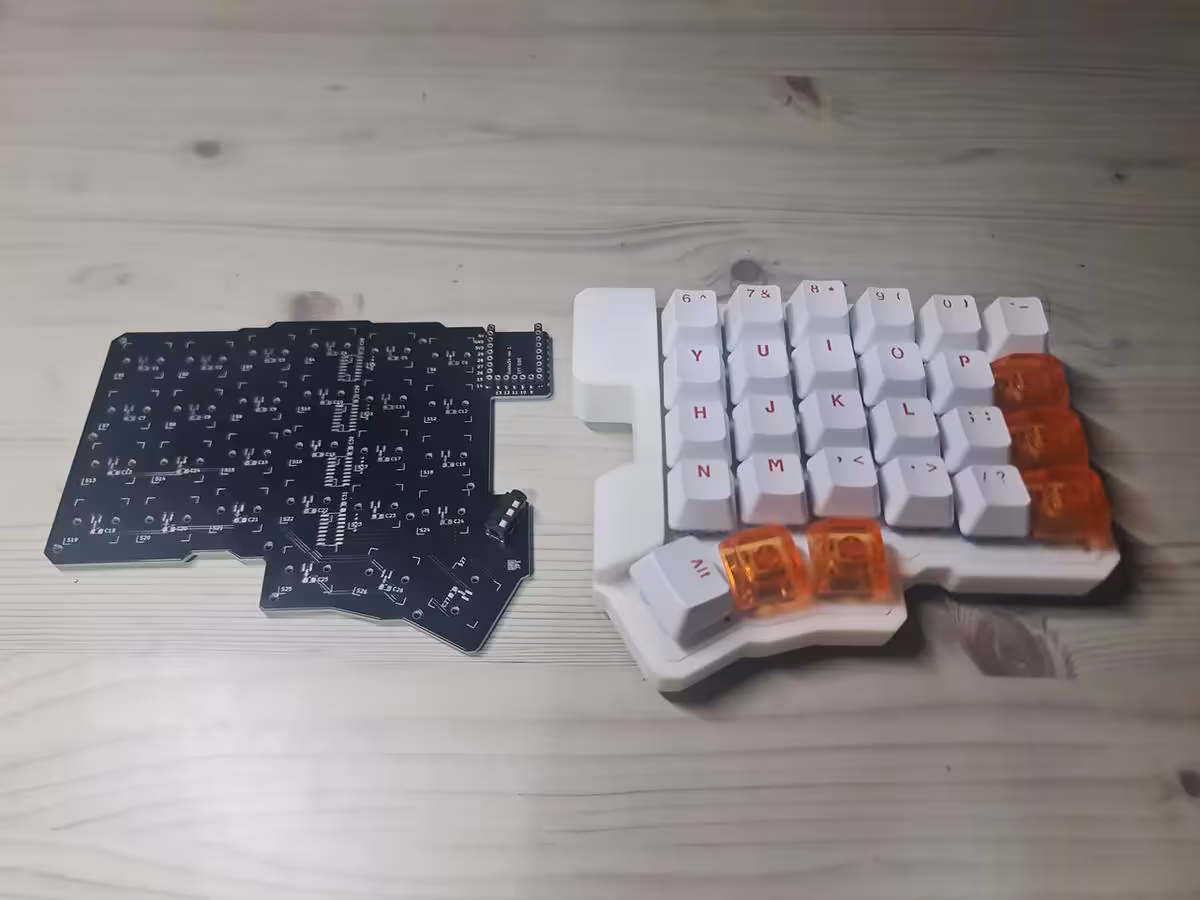 Clavier split magnétique blanc avec PCB noir exposé, modules séparés sur bureau en bois