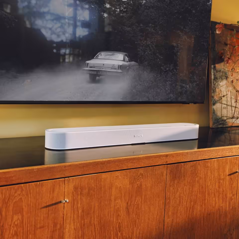 Barre de son Sonos blanche posée sous une télévision dans un salon