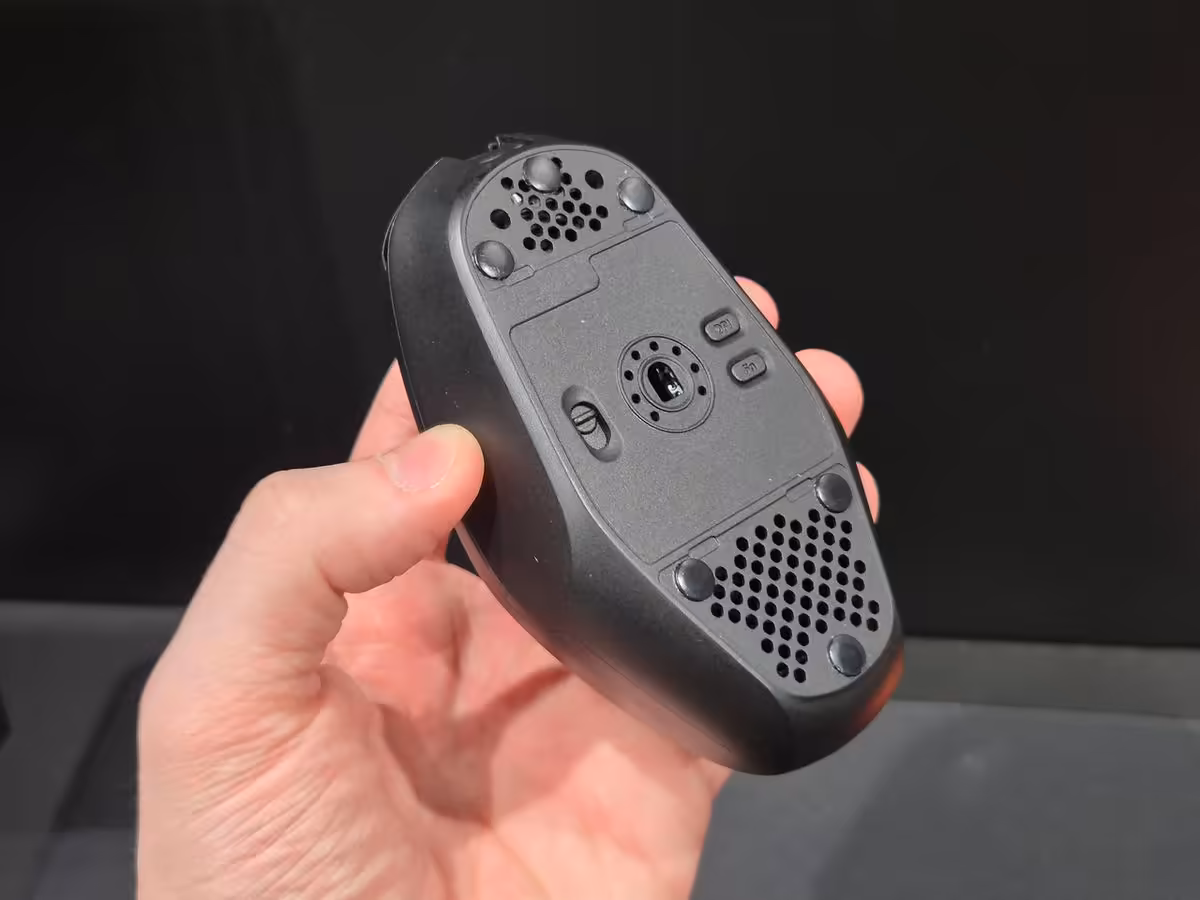 Teevolution Kira : une souris sans fil qui ressuscite clairement l’esprit de la Logitech G303 5 Dessous de la souris sans fil noire, avec capteur, patins et compartiment technique visibles
