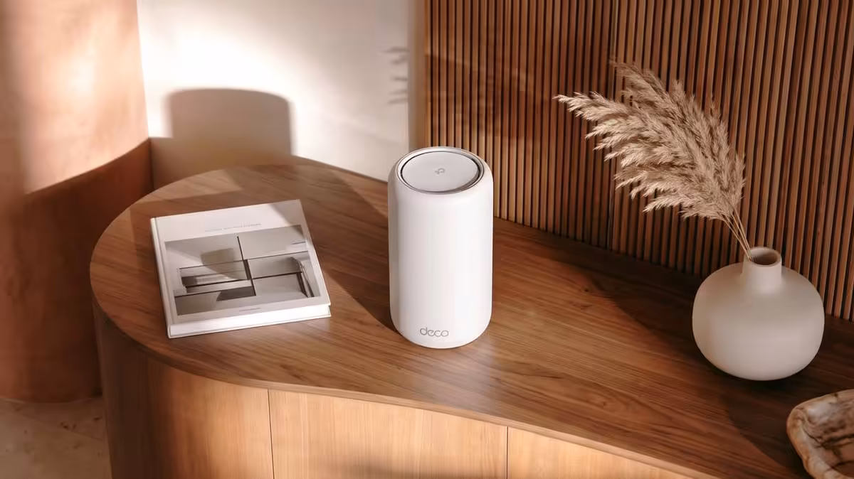 Wi‑Fi 8 : TP-Link dégaine déjà une gamme complète avec routeur Archer et mesh Deco 4 Routeur Wi‑Fi TP-Link blanc cylindrique sur table en bois, avec décor intérieur minimaliste