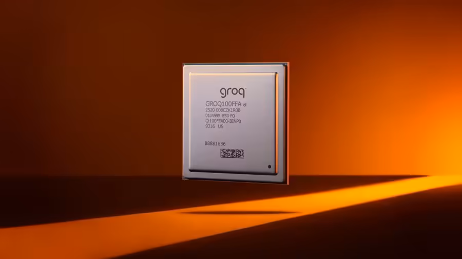 Puce d’inférence Groq LPU GROQCHIP sur fond orange, éclairée par un faisceau lumineux