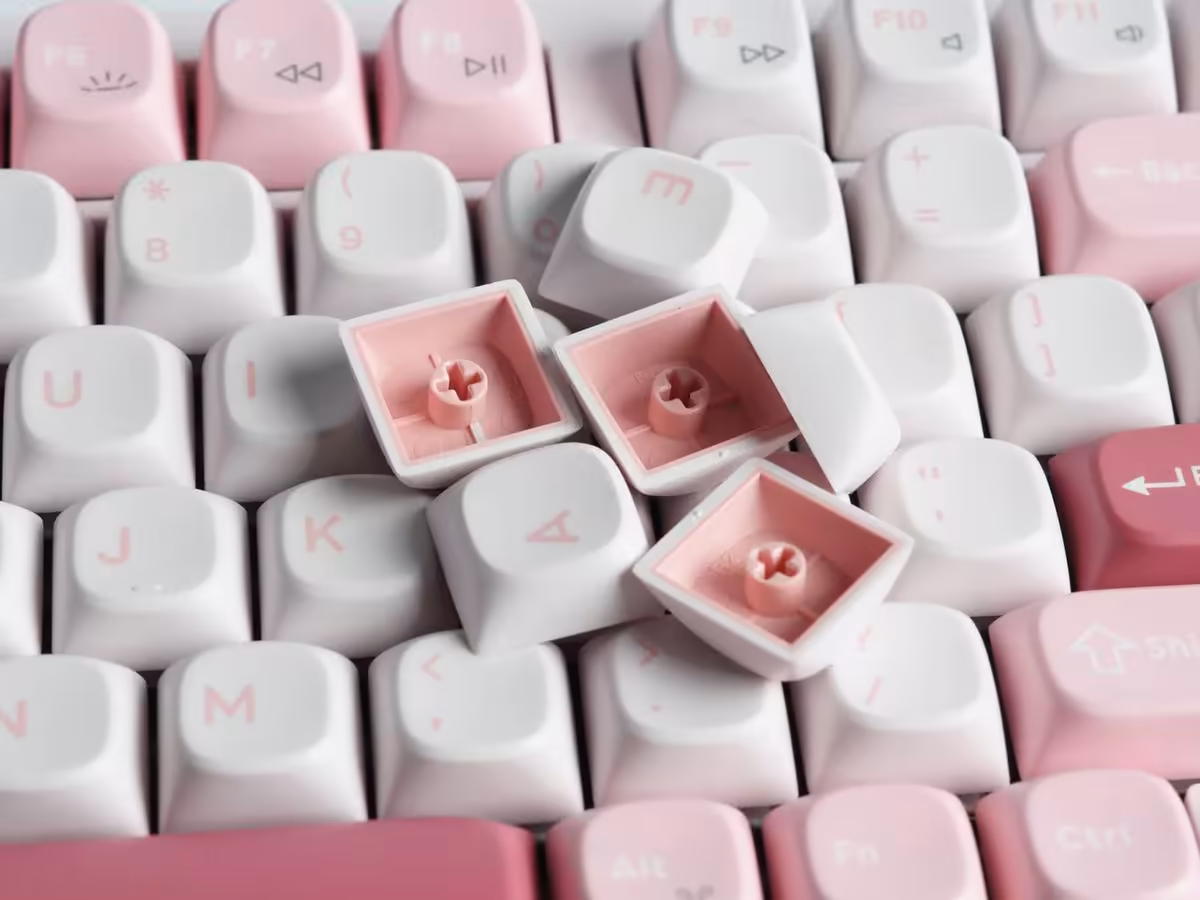 Gros plan sur les keycaps roses et blancs du clavier Keychron J3 SE avec switches exposés