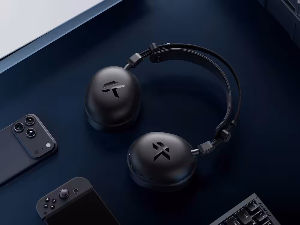 Mchose R9 : un casque gaming sans fil de 235 g annoncé à 150 heures d’autonomie 2 Casque gaming sans fil Mchose R9 noir posé sur un bureau avec smartphone, manette et clavier
