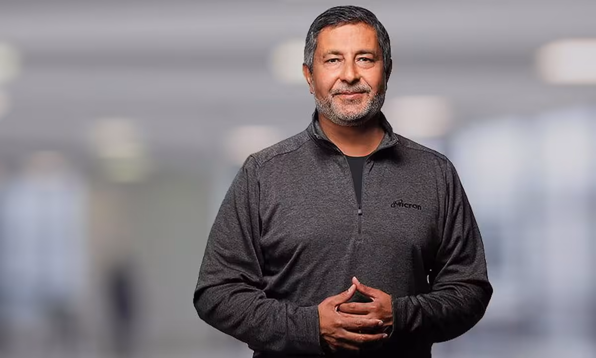 Dirigeant de Micron portant une veste grise dans un environnement industriel flou