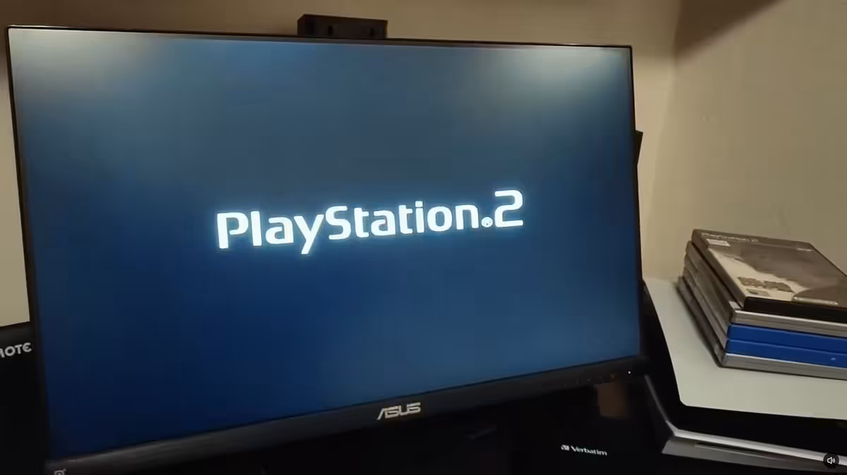 Écran ASUS affichant le logo PlayStation 2, avec boîtiers de jeux PS2 sur un bureau