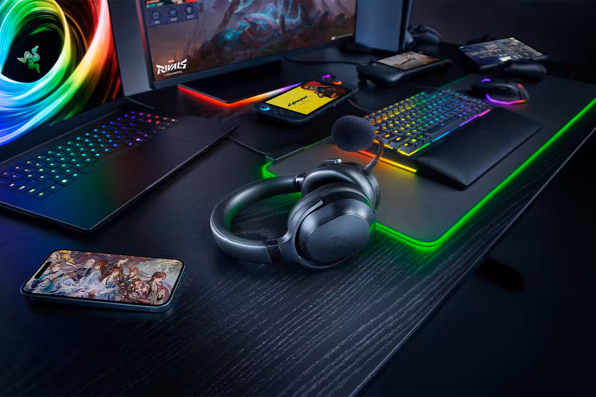 Razer Barracuda V2 Pro : ANC hybride, double connexion et 70 heures d’autonomie 7 Casque Razer Barracuda V2 Pro sur setup gaming RGB avec ordinateur portable, clavier et smartphone