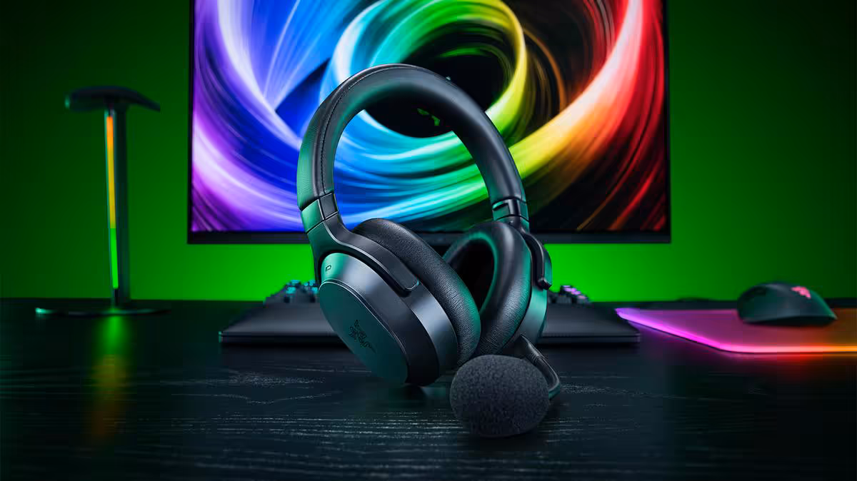 Razer Barracuda V2 Pro : ANC hybride, double connexion et 70 heures d’autonomie 2 Casque gaming Razer Barracuda V2 Pro avec microphone sur bureau devant écran RGB