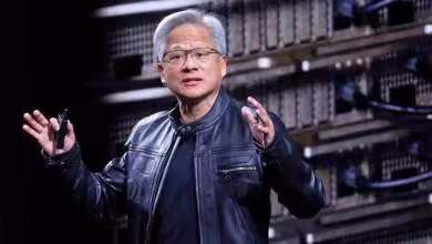 Jensen Huang, PDG de NVIDIA, présente devant des racks de serveurs lors d’une conférence