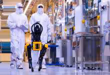 Techniciens Micron en salle blanche testant un robot industriel dans une usine de fabrication de mémoire
