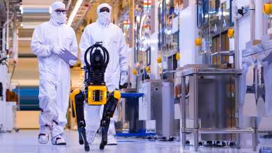 Techniciens Micron en salle blanche testant un robot industriel dans une usine de fabrication de mémoire