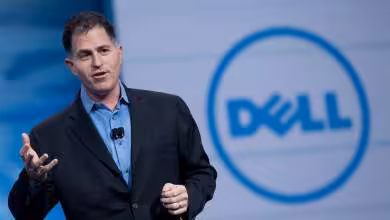 Michael Dell en costume lors d’une conférence, devant le logo Dell affiché sur grand écran