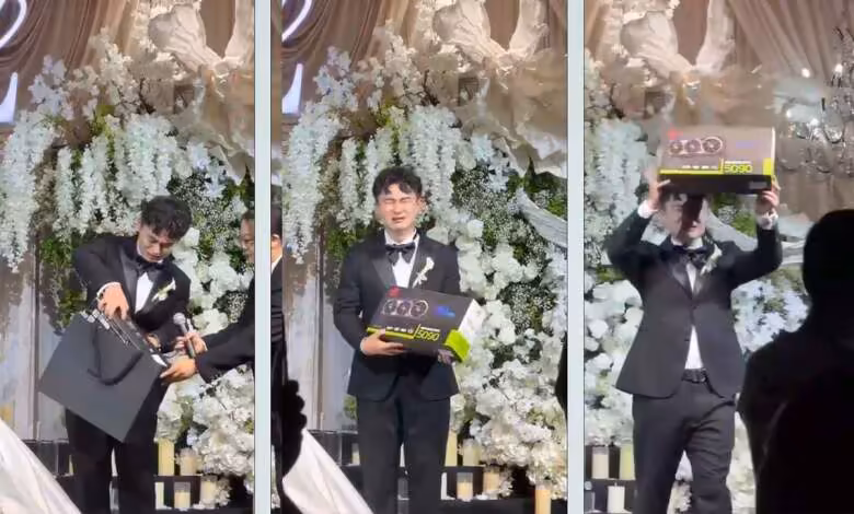 RTX 5090 : une ASUS ROG Astral à 12 000 dollars offerte lors d’un mariage 1 Homme en costume présentant une carte graphique ASUS ROG Astral RTX 5090 lors d’une cérémonie décorée de fleurs