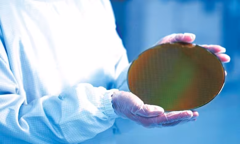 Samsung 2 nm : l’usine texane viserait 20 000 wafers mensuels dès 2027 1 Technicien en combinaison blanche tenant une tranche de silicium dans une salle blanche de fabrication de puces