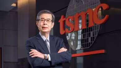 Dirigeant de TSMC en costume devant le logo rouge de l’entreprise et une façade vitrée