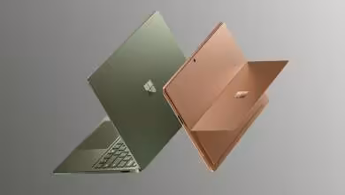Deux ordinateurs portables Microsoft Surface verts et cuivre flottant sur fond gris, vus de dos et de profil